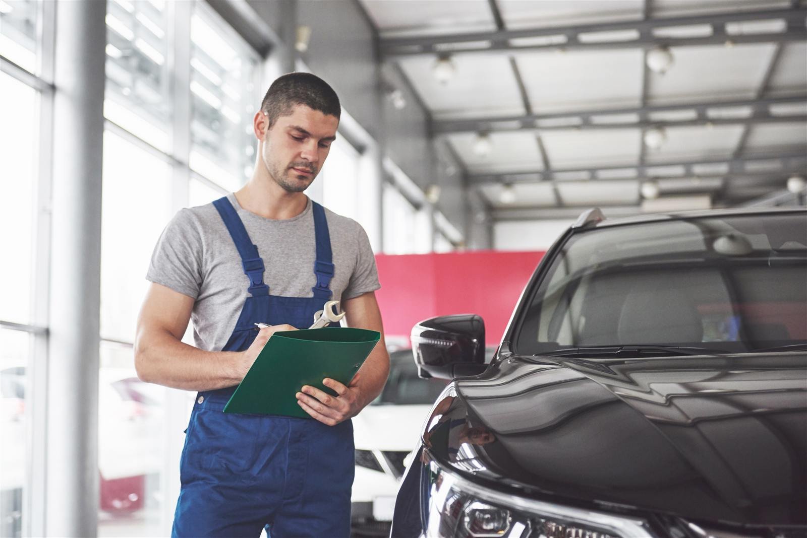 Mecânico anotando a avaliação de um carro na oficina