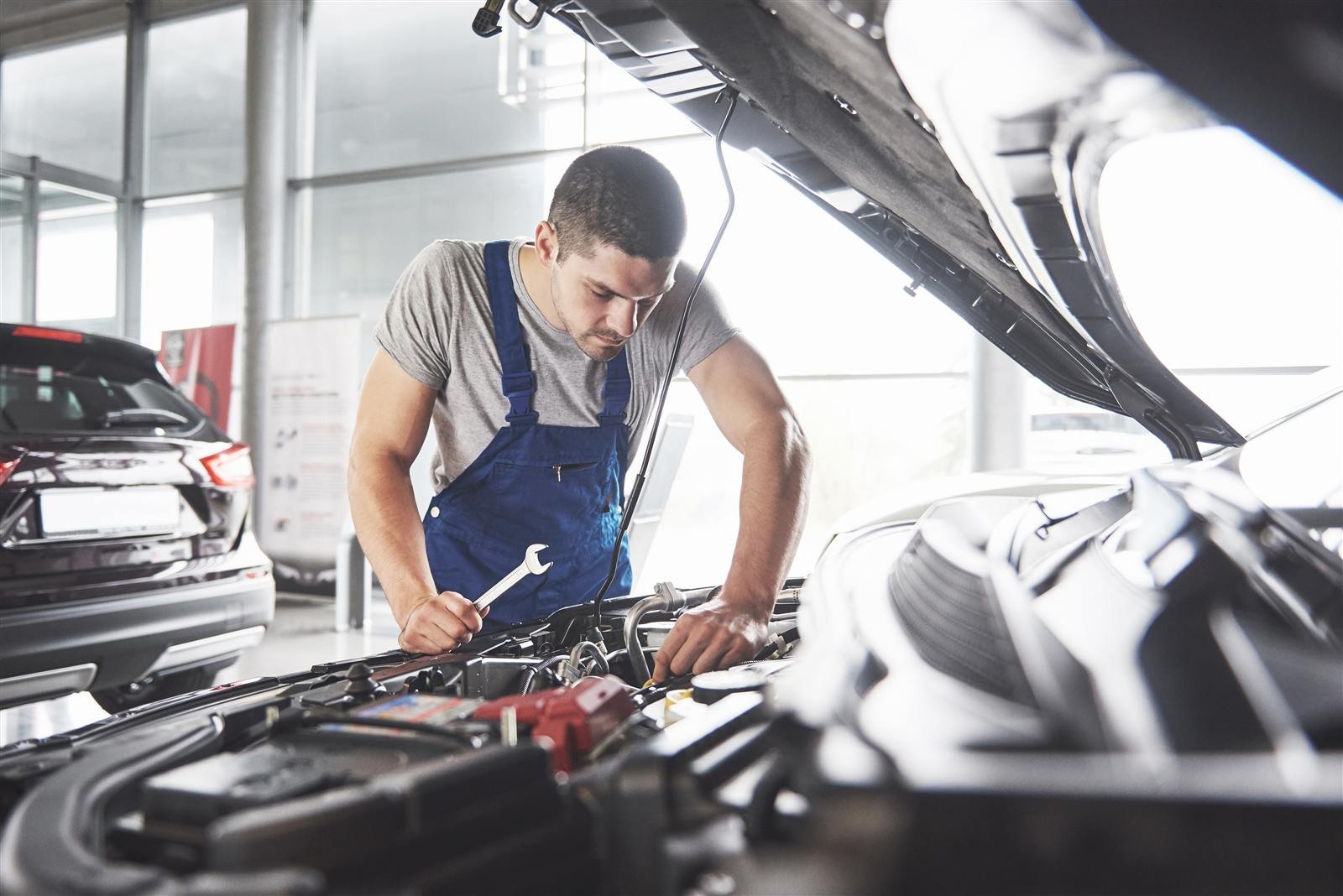 Mecânico checando o motor de um carro com o capô aberto
